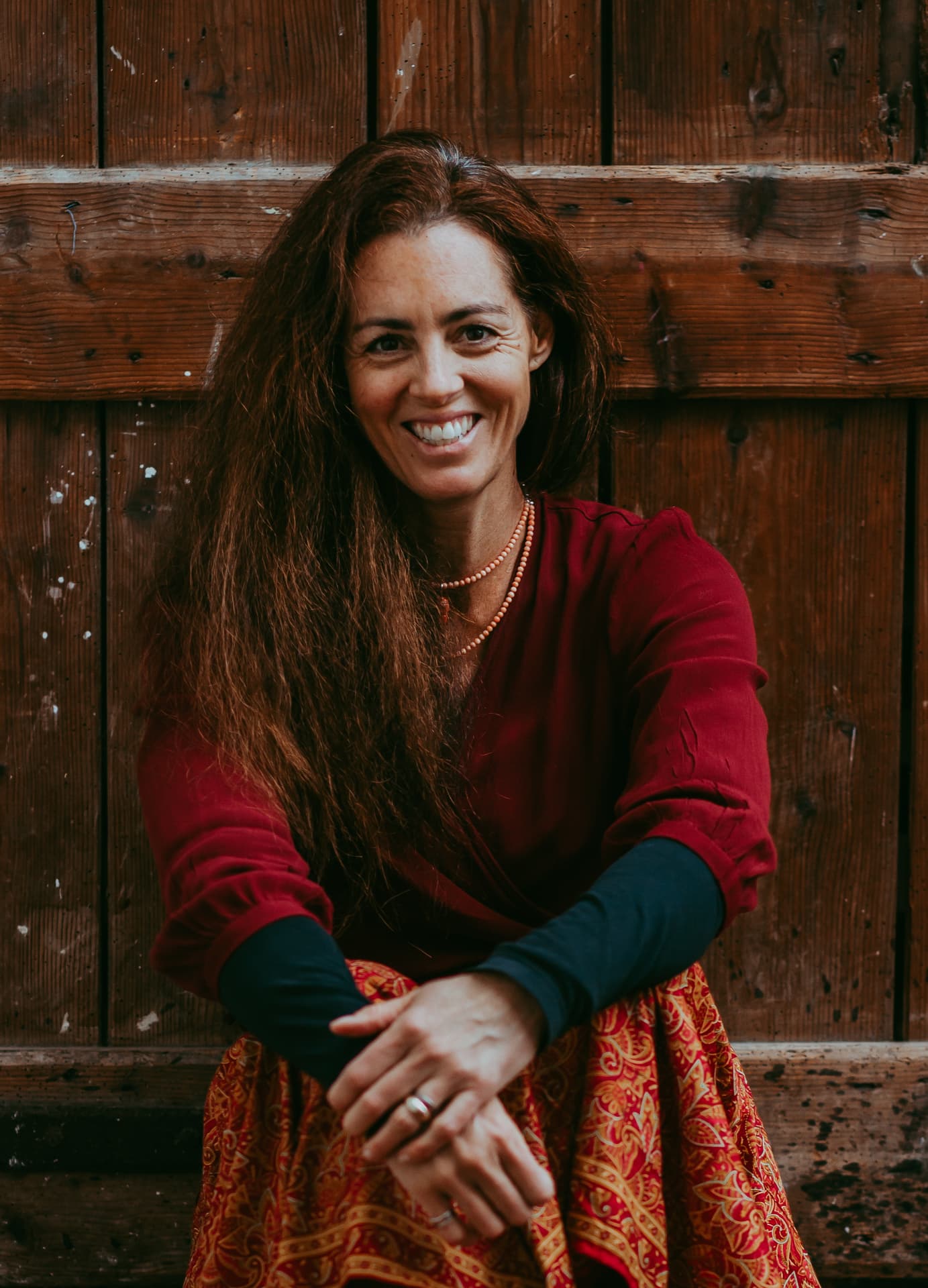 Katherine Crawley smiling, seated against a wooden barn door